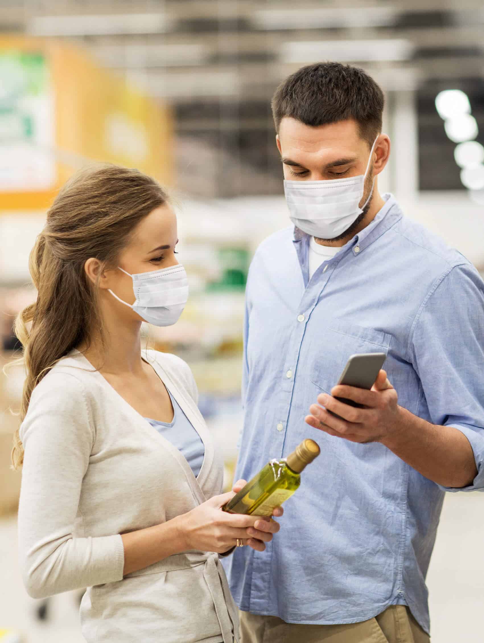 Man and woman grocery shopping while looking at a phone